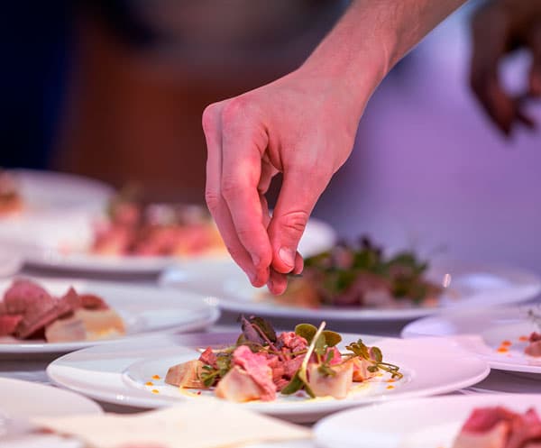 Koch richtet essen auf Teller an