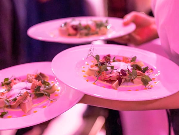 Kellner trägt drei angerichtete Teller mit Fleisch und Gemüse